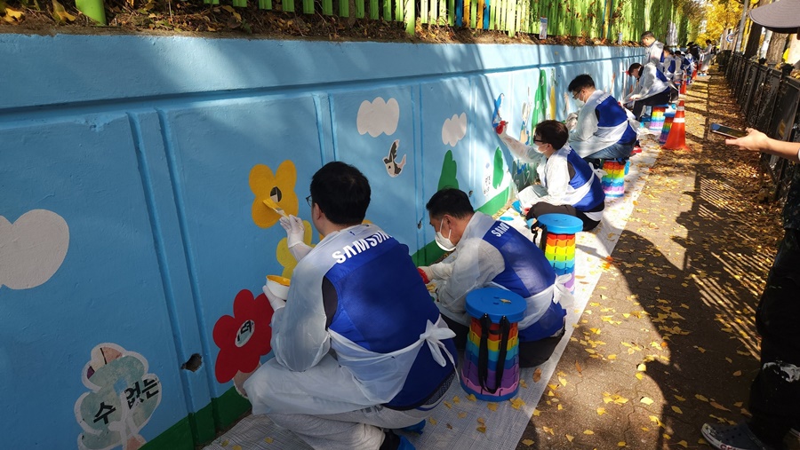 삼성전자 임직원들이 12일 수원시 권선구 구운초등학교에서 벽화 그리기 봉사 활동에 참여하고 있다.[사진=삼성전자]